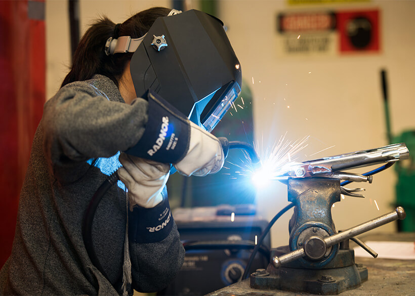 Student welding in the auto collision workshop