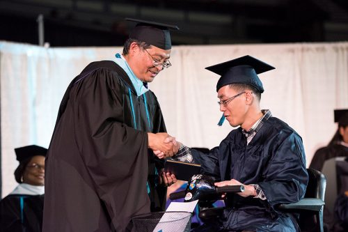 Student in electric scooter receiving diploma