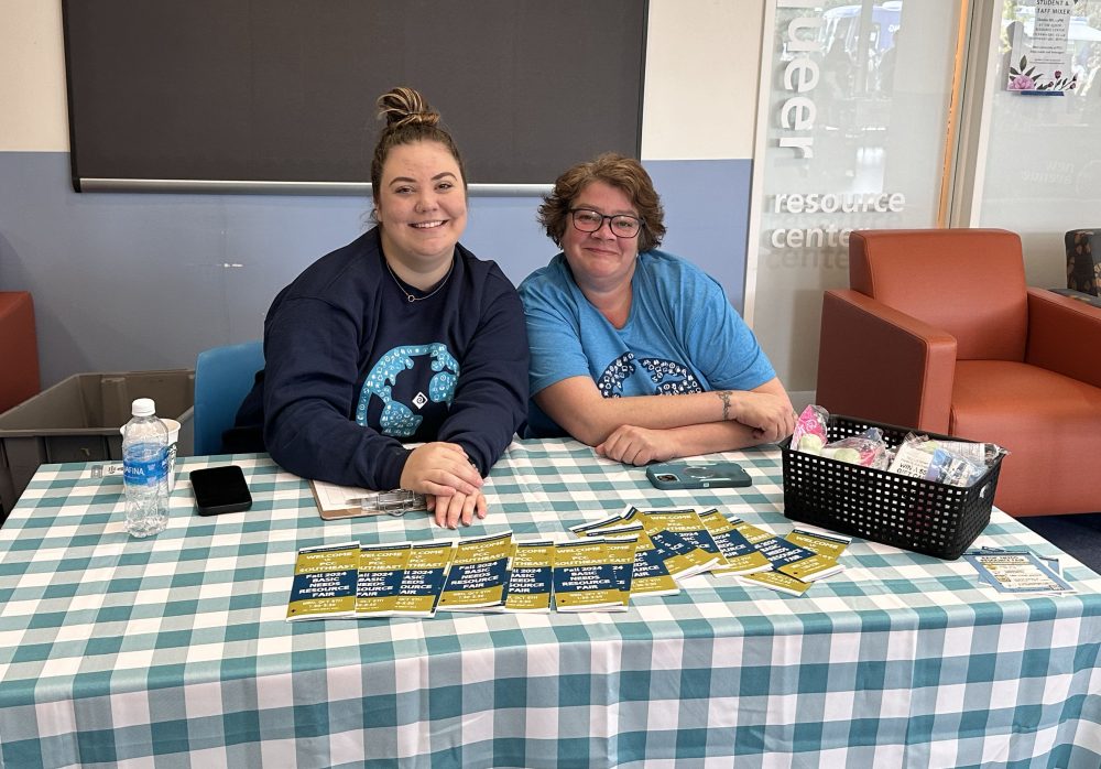 Smiling staff tabling at a basic needs resource fair
