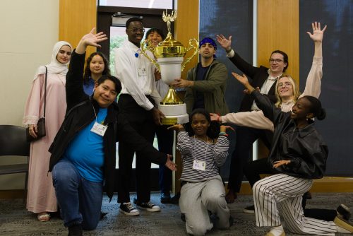ASPCC students posing enthusiastically with a large trophy.