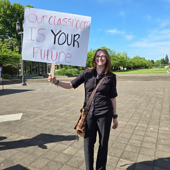 Student marching with "Our classroom is your future" protest sign