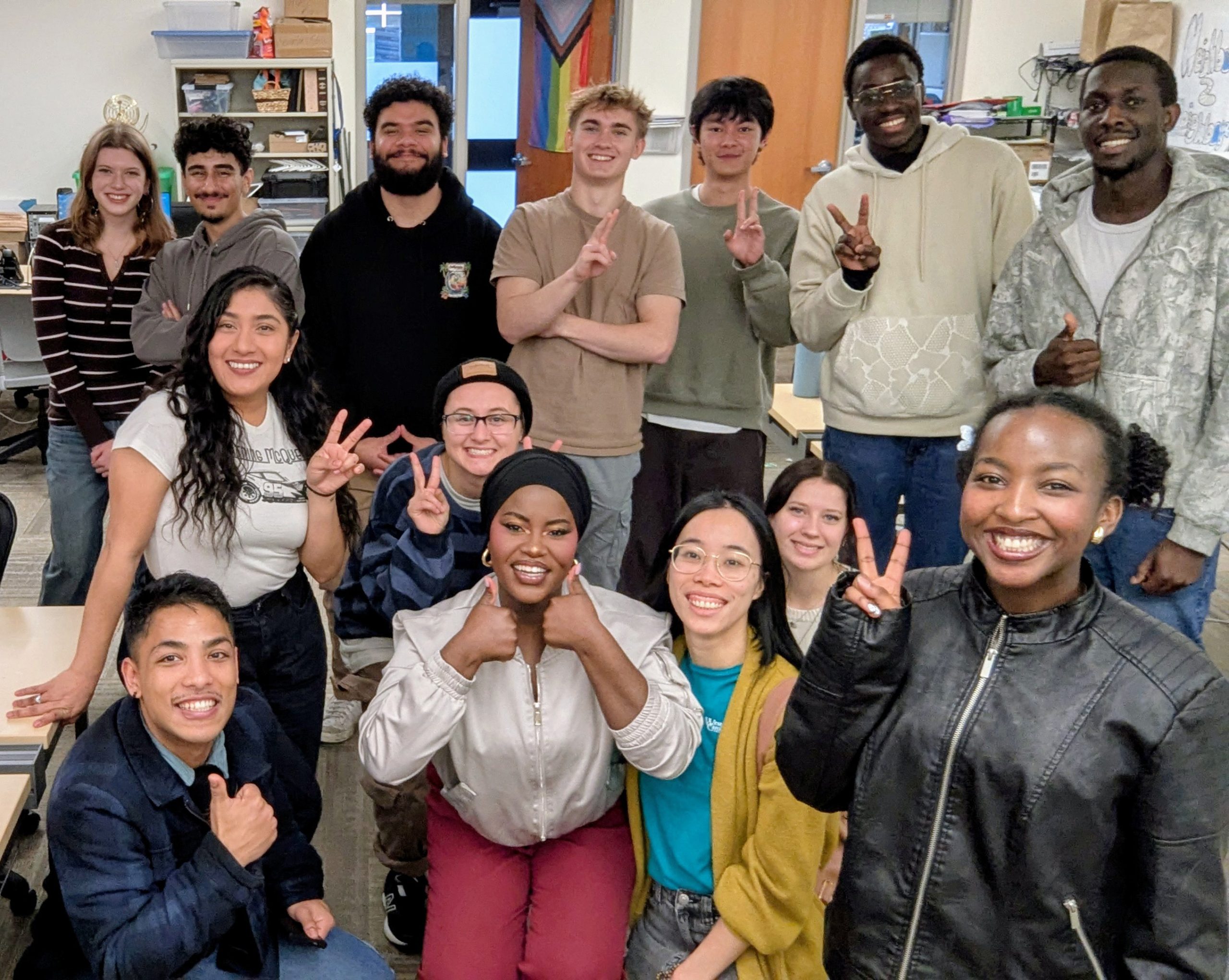 Grinning group photo with peace signs and thumbs up