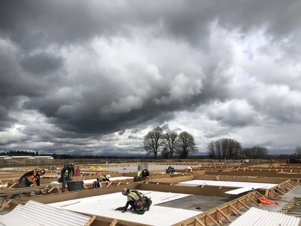 People working on the construction site under dramatic gray clouds