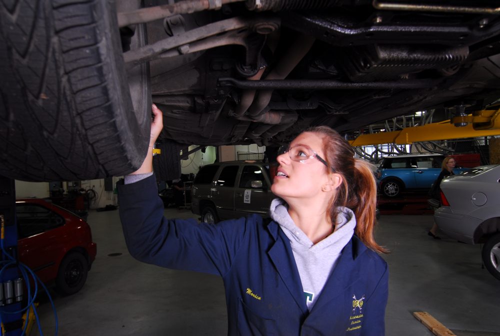 Automotive Services student looking under a car