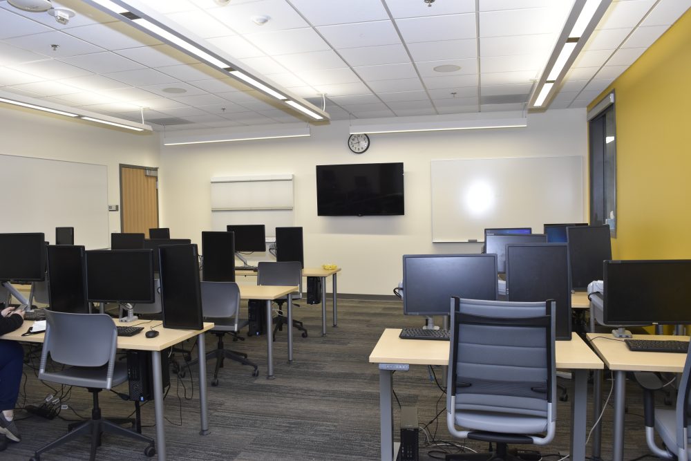 Room full of computers with a with board at the front of the room