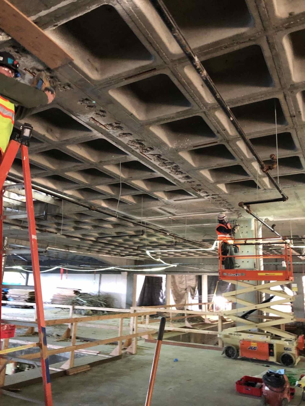 Construction workers on ladders preparing existing beams
