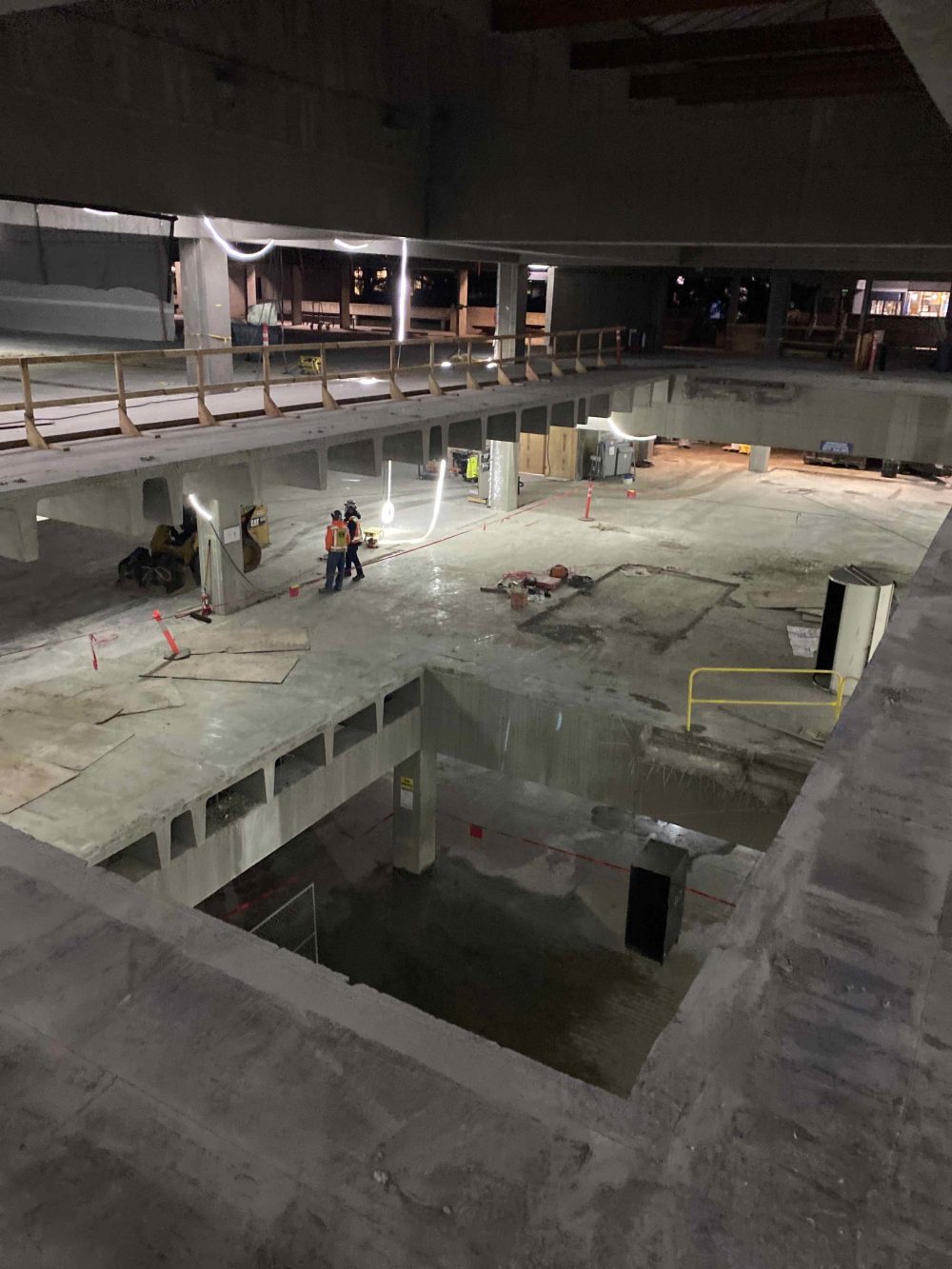 Opening through the HT building where once the staircase used to be, construction crew installing guardrails and lights