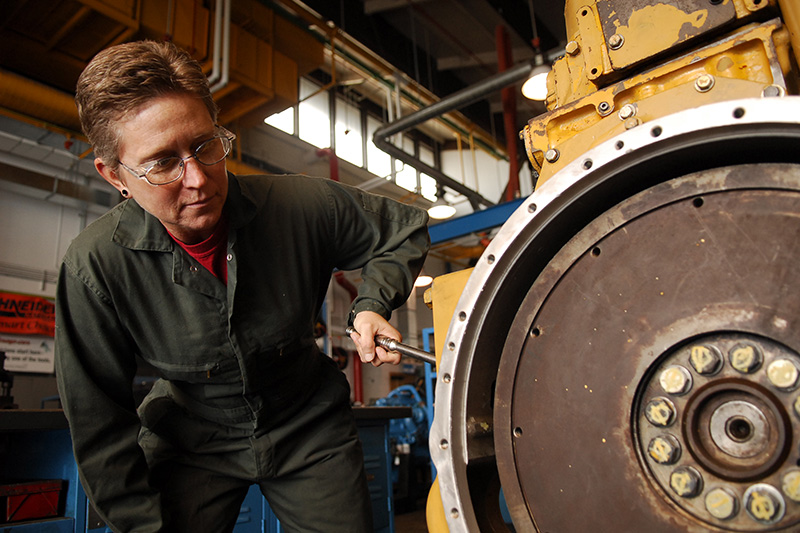 Student working on a CAT machine with a screwdriver