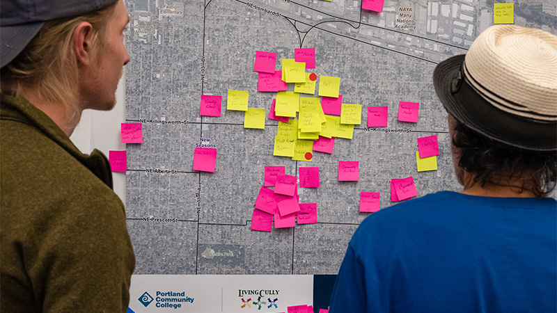 People looking at sticky notes with messages on a map of northeast Portland