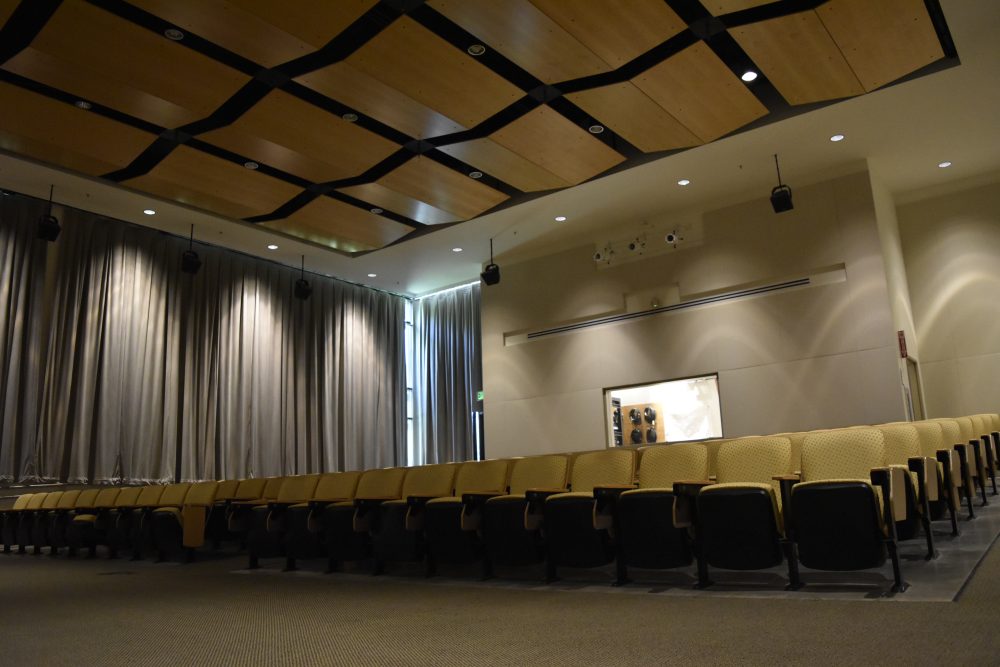 Moriarty Auditorium extensive seating seen from the front, curtains cover the window on the back of the room