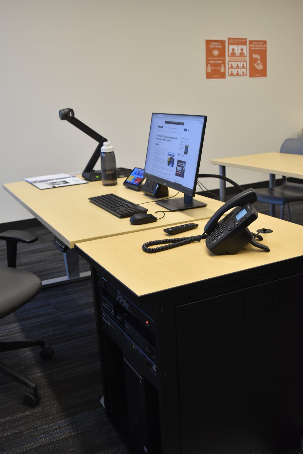Presenter's table in the classroom, housing the touch screen control, monitor, keyboard, mouse, phone and document projector