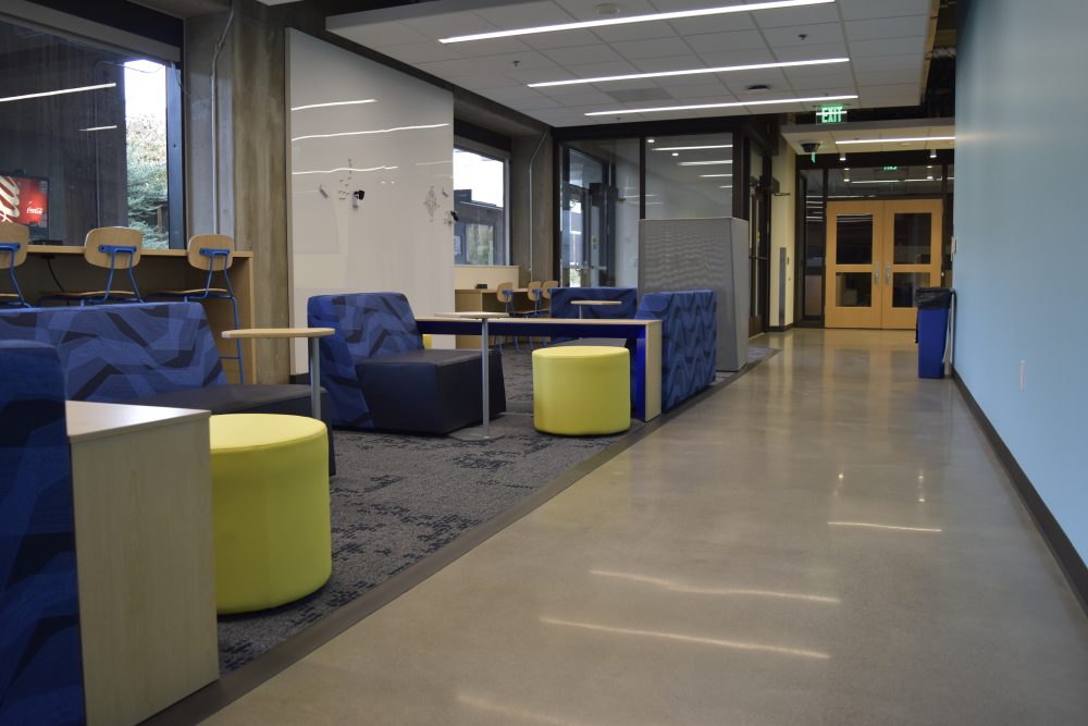 Different seating area, some soft seating, some hard chairs frame a hallway in ST building.