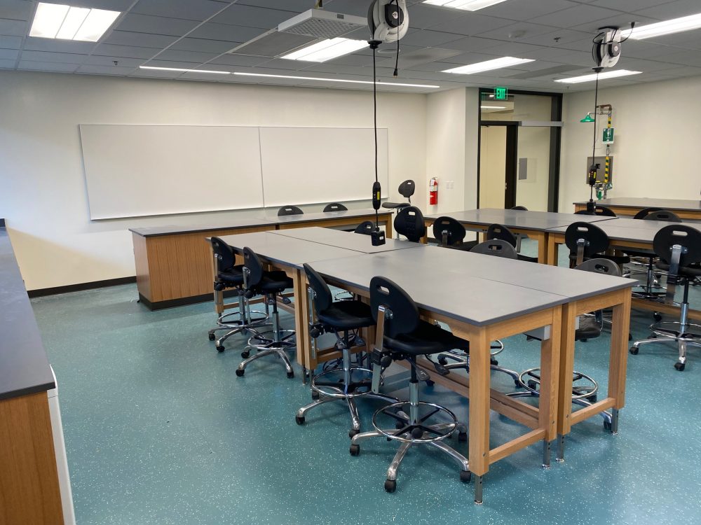 Biology lab in ST second floor showing high chairs around rectangle tables formed by four smaller, rectangular tables