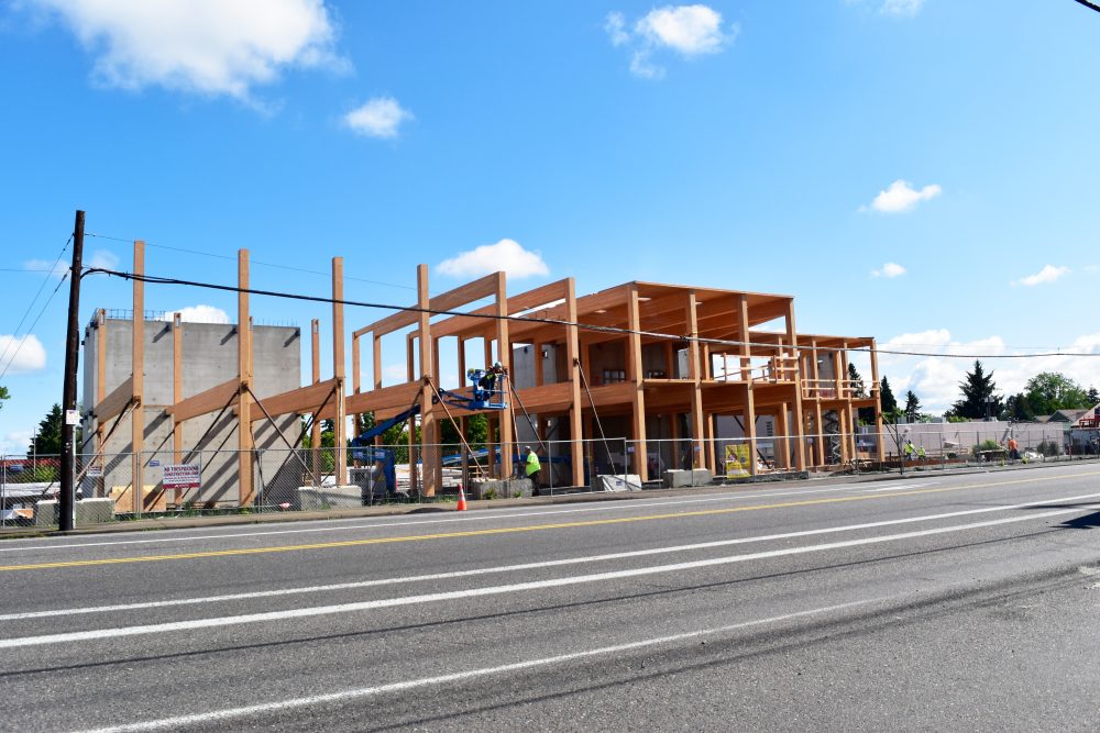 Construction site looking NE, showing workers installing first structural beams