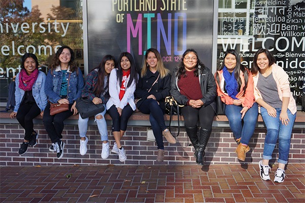 Students sitting on a brick wall in a group