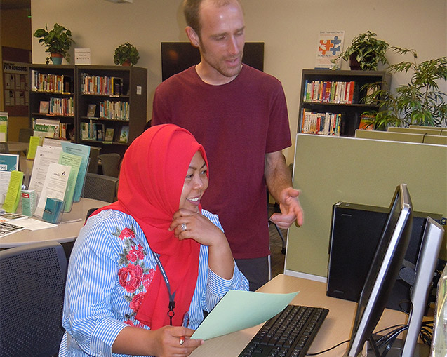 Peer advisor helping a student at a computer