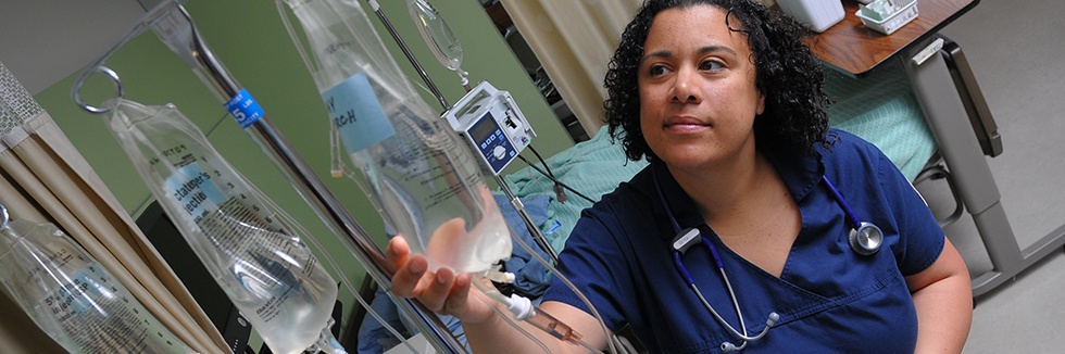 student in scrubs hangs IV bag