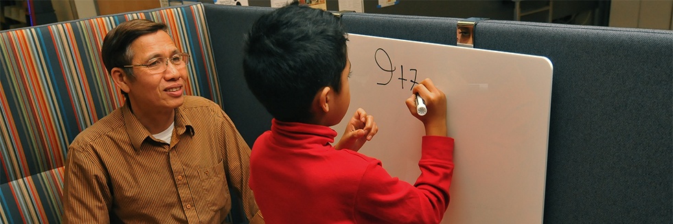 man and child write on whiteboard