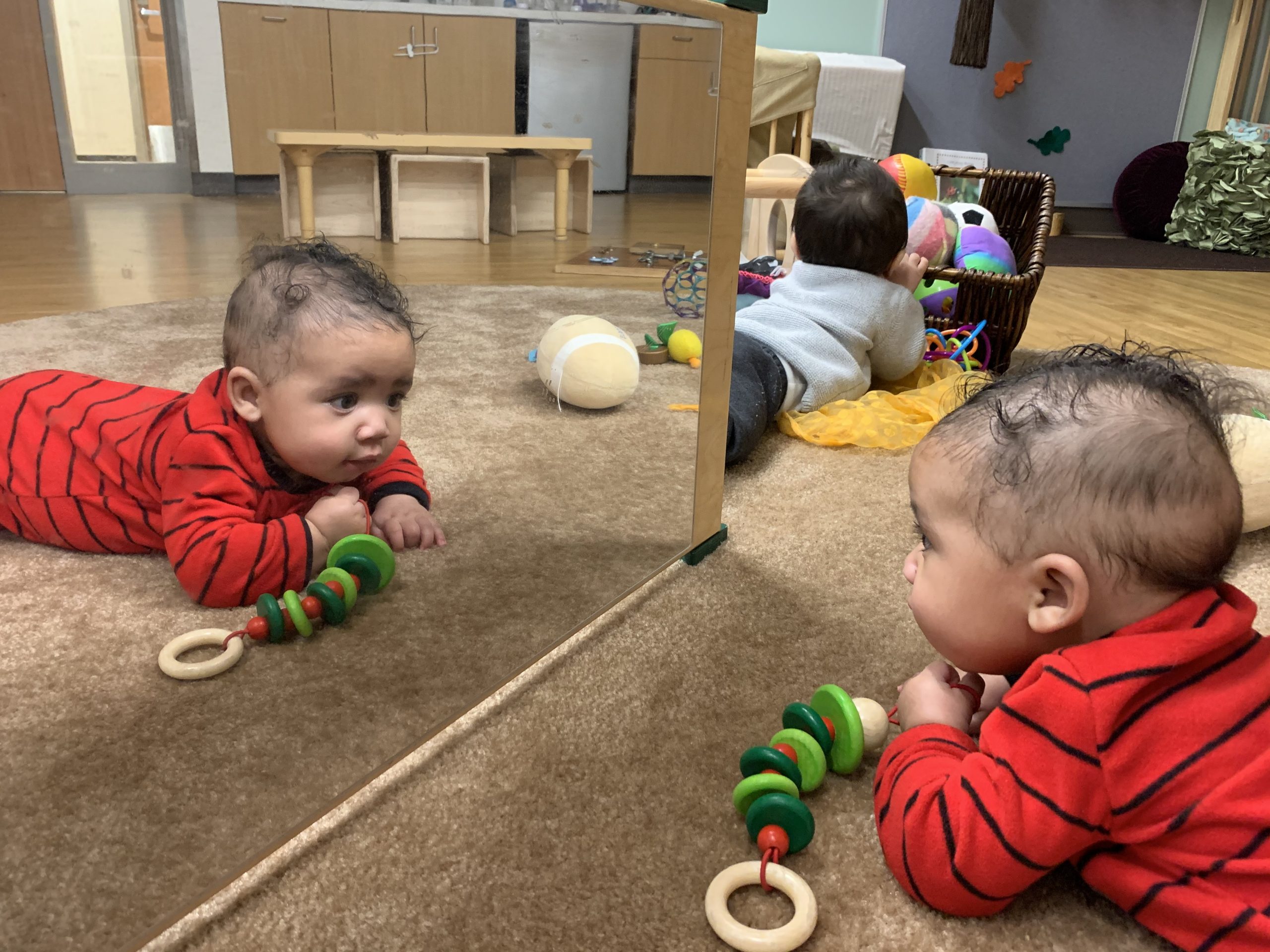 Baby looking carefully at himself in the mirror