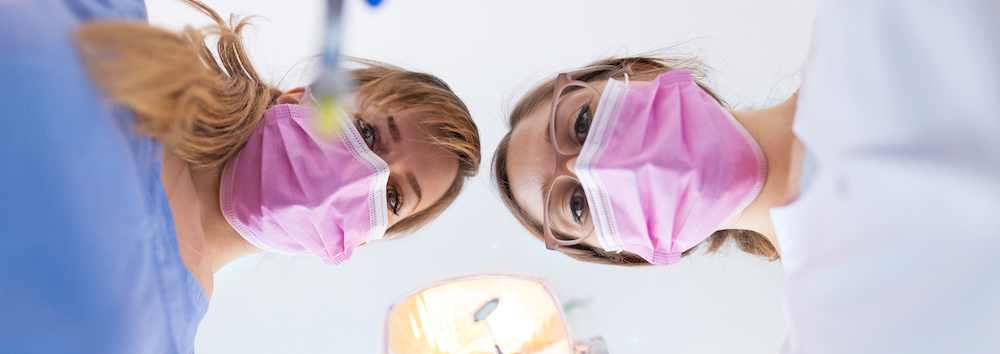 Female dental assistants work on patient