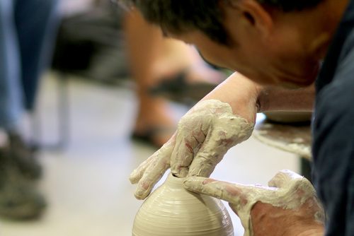Student throwing a pot on the wheel in a ceramics class