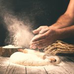 Man preparing bread dough on wooden table in a bakery