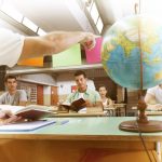 group of students follow the lesson in a classroom with a globe in the photo