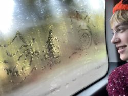 PCC Student Haley Swain looks out the window en route to Tillamook State Forest. Designs in the shape of a sun, a tree, and a river have been drawn into the fogged window with Haley's finger. 