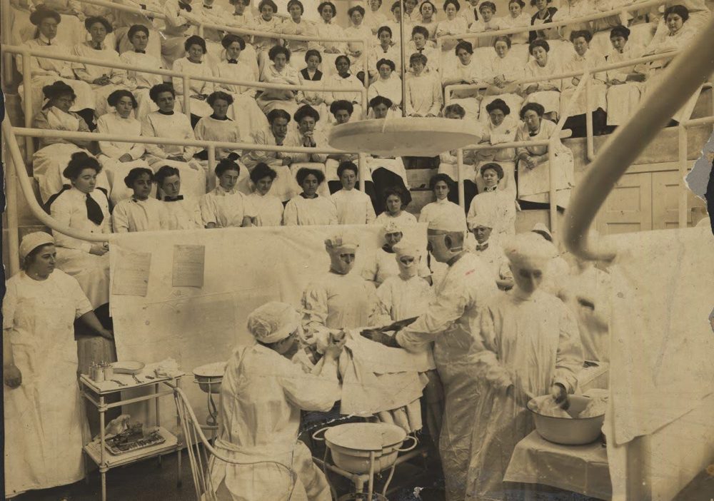 Women performing surgery in a medical amphitheater.
