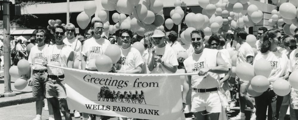 Black and white photo of men holding a banner that says greetings from Wells Fargo bank.