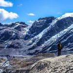 Photo of rocky mountains with some snow, hikers standing in the foreground.