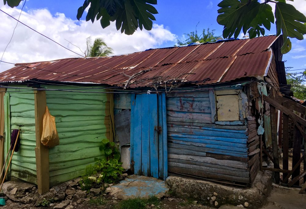Photo of a wood structure painted bright green and blue with a metal roof.