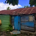 Photo of a wood structure painted bright green and blue with a metal roof.