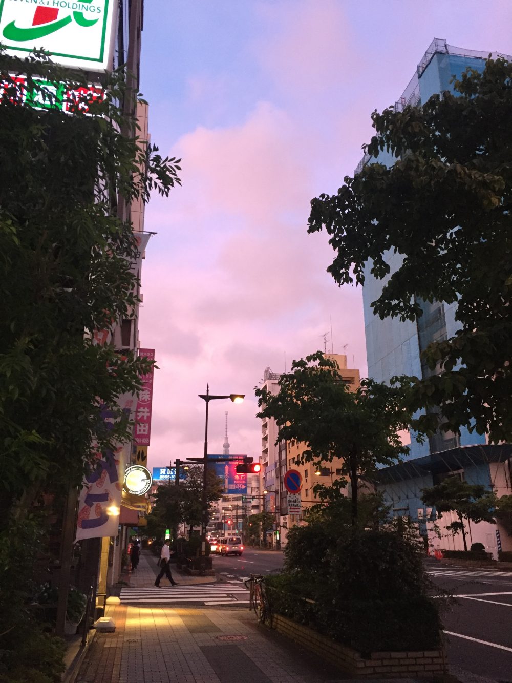 A photo of a city street at sunrise, with a light pink and blue sky.