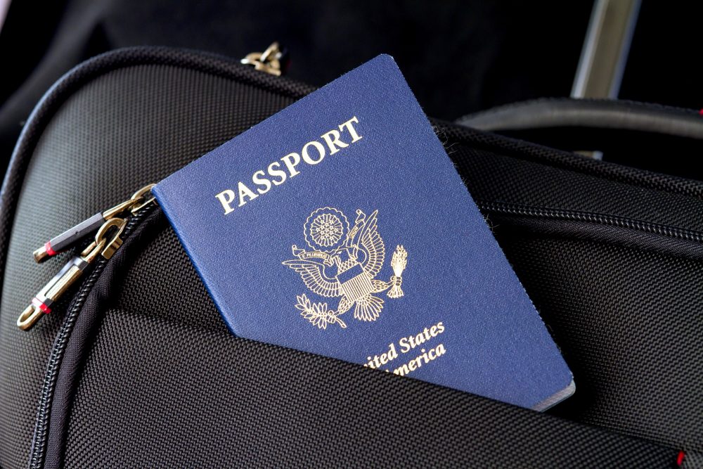 Blue US passport sticking out of a suitcase pocket