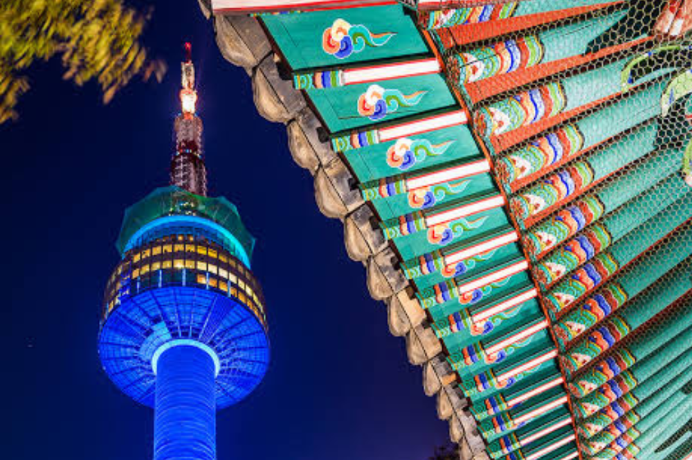 colorful tiles on the roof of a traditional temple with a large tower in the background