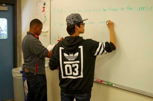 two students writing on the white board