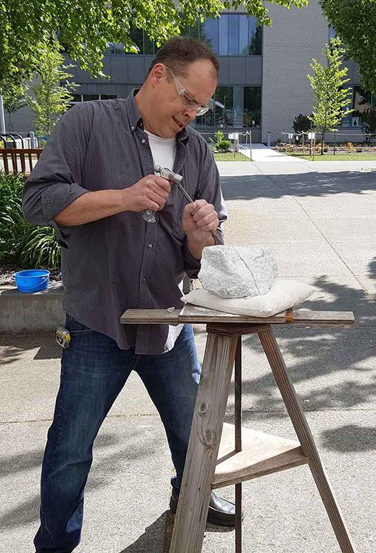 man carving a large piece of stone