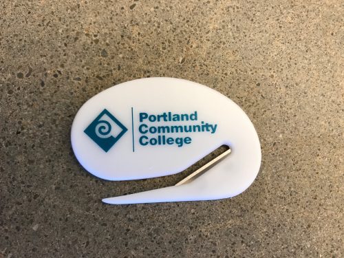 White rounded letter opener with a turquoise PCC logo