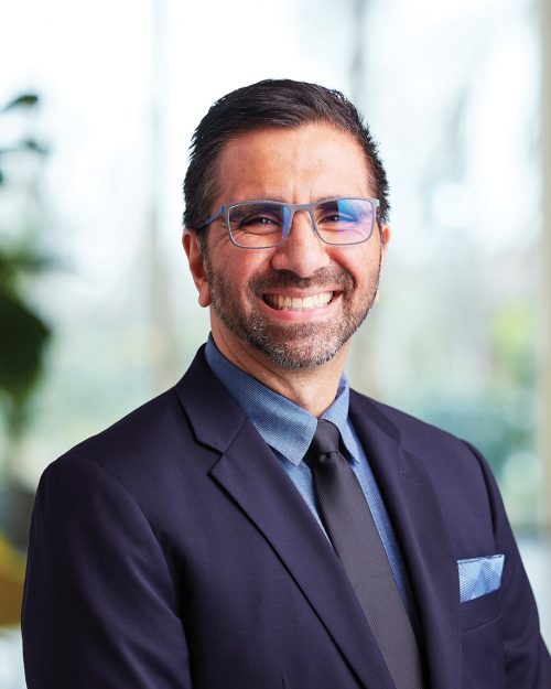 Man wearing glasses smiling and looking directly at camera.