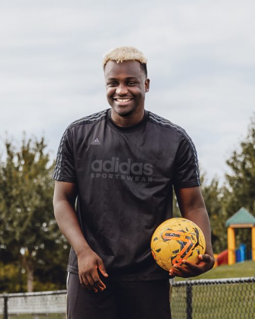 PCC student holding a soccer ball and smiling at camera.
