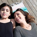 Woman and daughter laying on a blanket and smiling