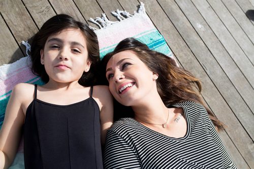 Woman and daughter laying on a blanket and smiling