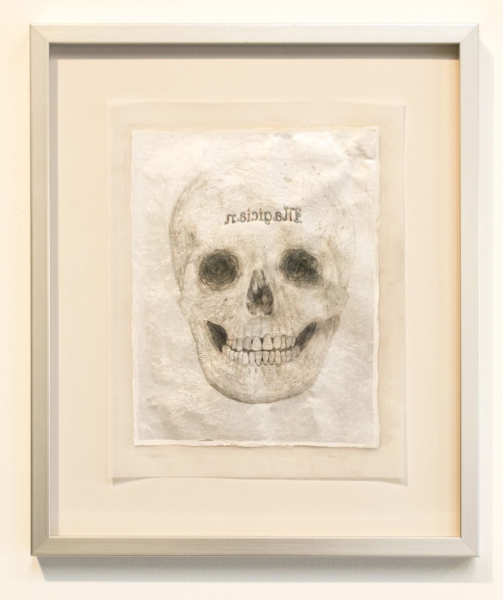 Framed drawing of skull; primarily black and shades of gray, with silver.