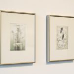 Two framed drawings on wall; one with a fish and industrial pipes; the other of black birds in the midst of wires.