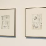 Two framed drawings on wall; both have birds and wires and telephone poles.