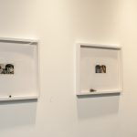 Three framed prints on wall; each has a small printed image of figures at the center, and a small lock of human hair at the bottom of the frame.