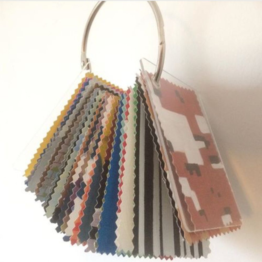 Sculpture consisting of a large metal ring with a series of small paintings on paper hanging from it. The paintings are grommeted on the end attached to the ring and have colorful abstract images on them.