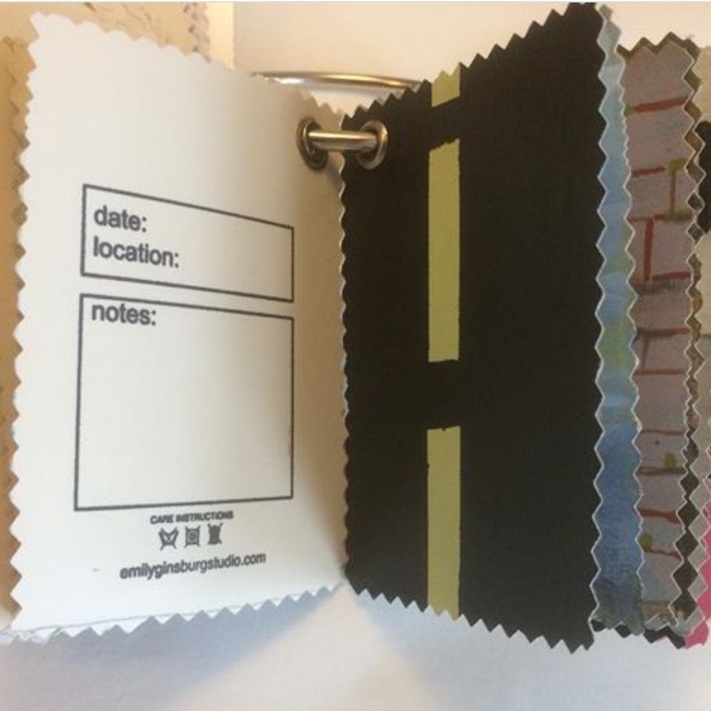 Sculpture with a series of small paintings on paper that have holes in one corner. They are strung together on a metal ring. On the left is one painting has text, on the right a number of paintings show abstract color images.