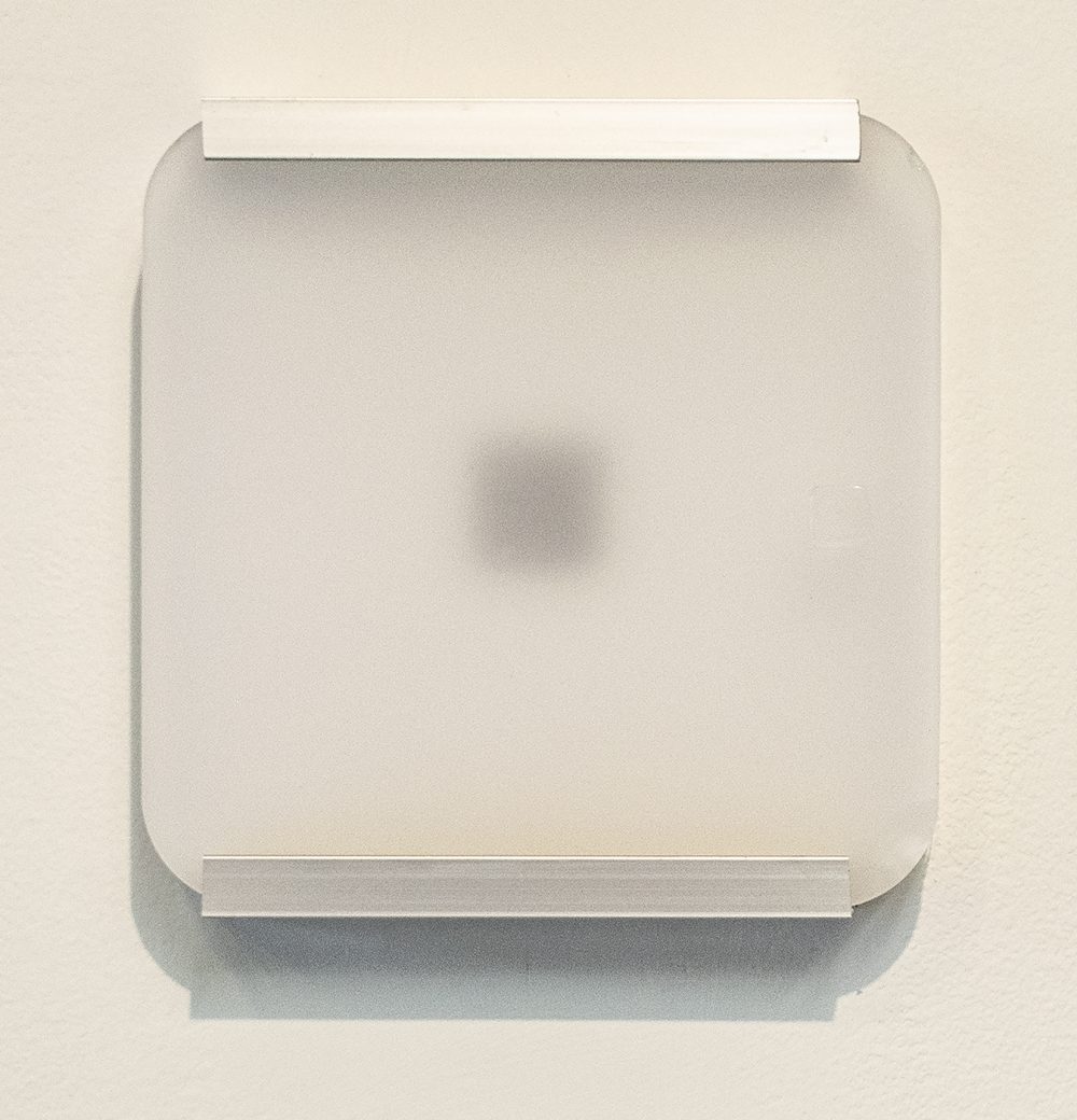 An square frosted acrylic panel sits on a metal framework. Seen through the panel, centered on the square shape, is a QRC code.